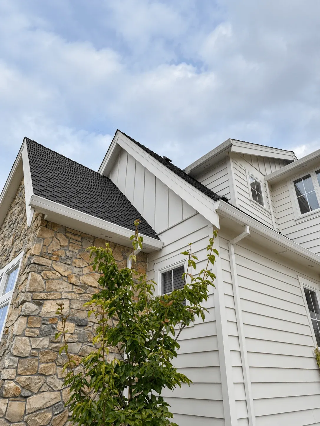 White board-and-batten siding meeting a stacked stone corner