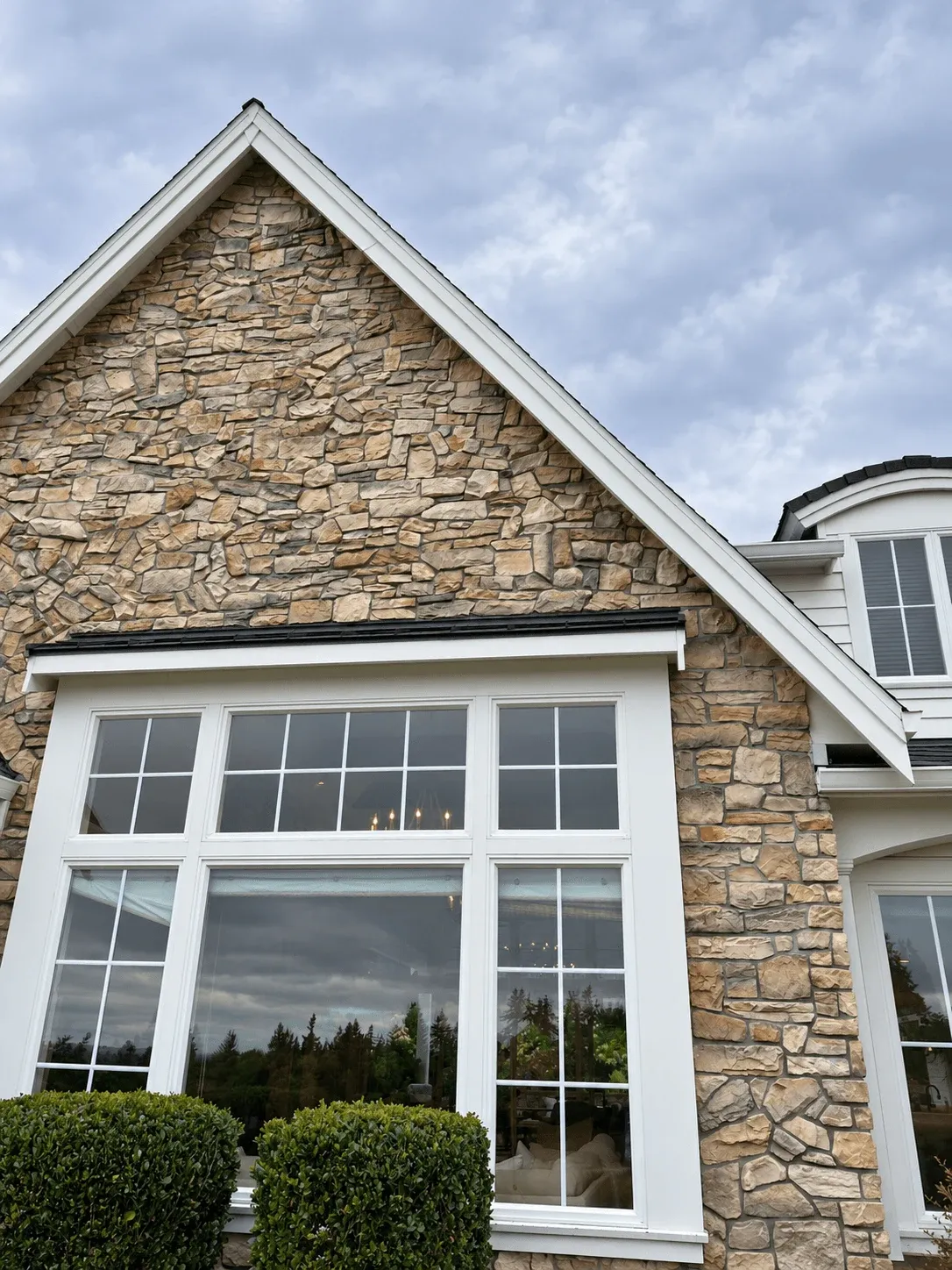 Stacked stone gable around a large grid window with white trim